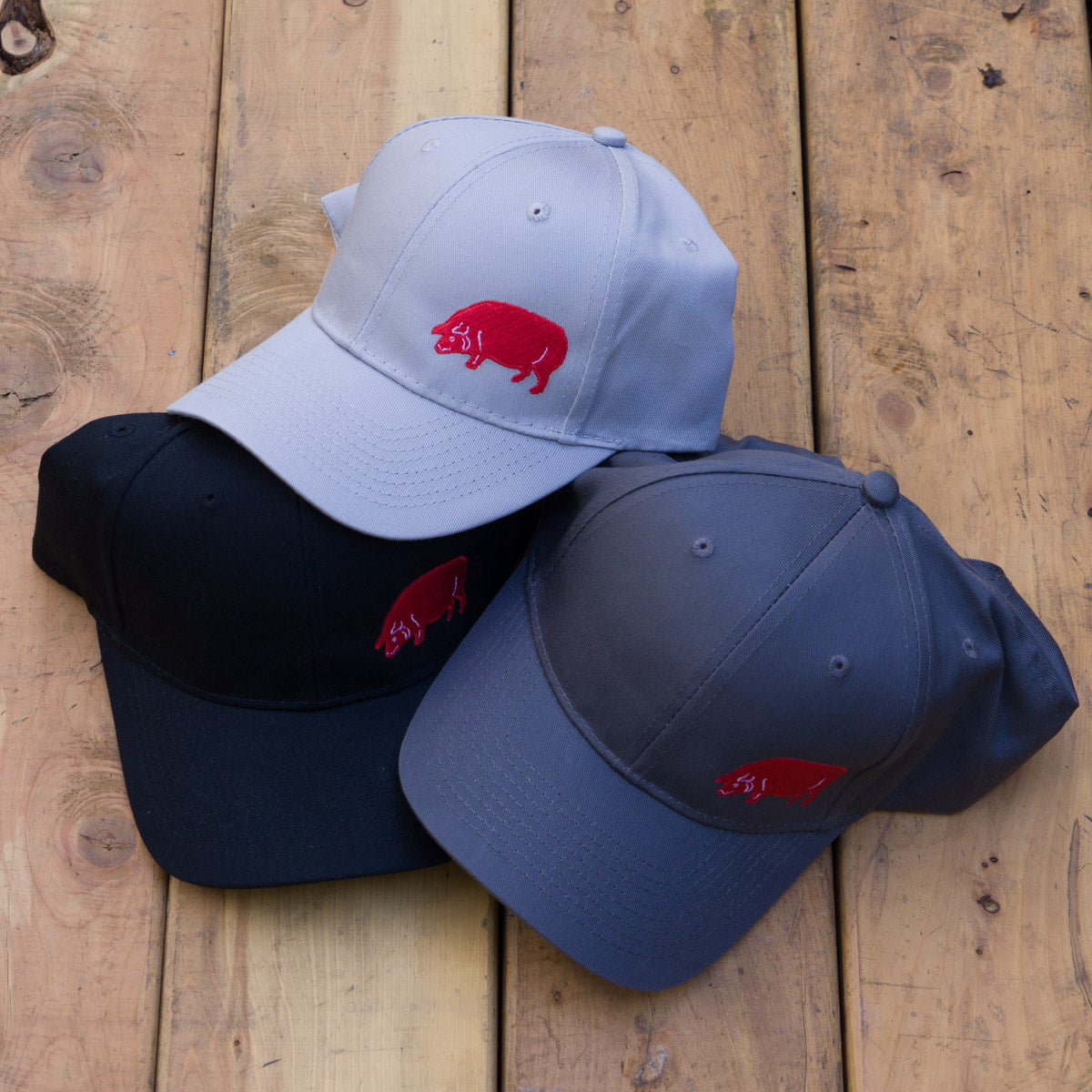 The lone Red Pig is embroidered to the side on these hats. Available in three colors: Black, Grey, and Light Grey.