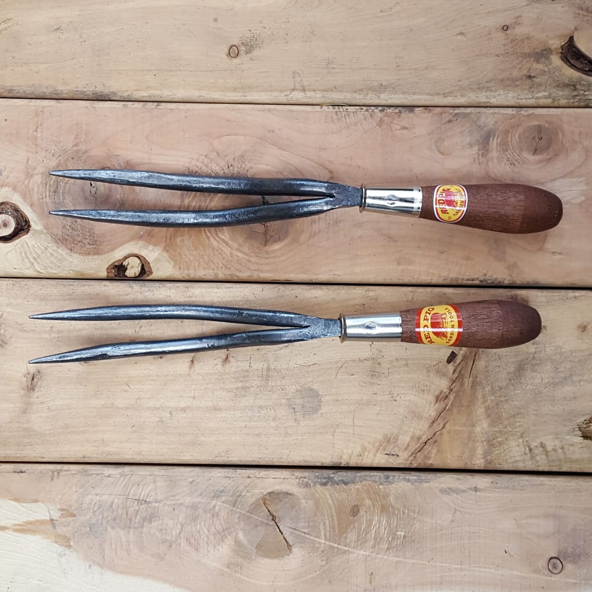 A sharply pointed two-tined weeder with a gentle curve for getting down deep into the earth, most often forged from 7/16" steel a 1/2" version is available upon request.