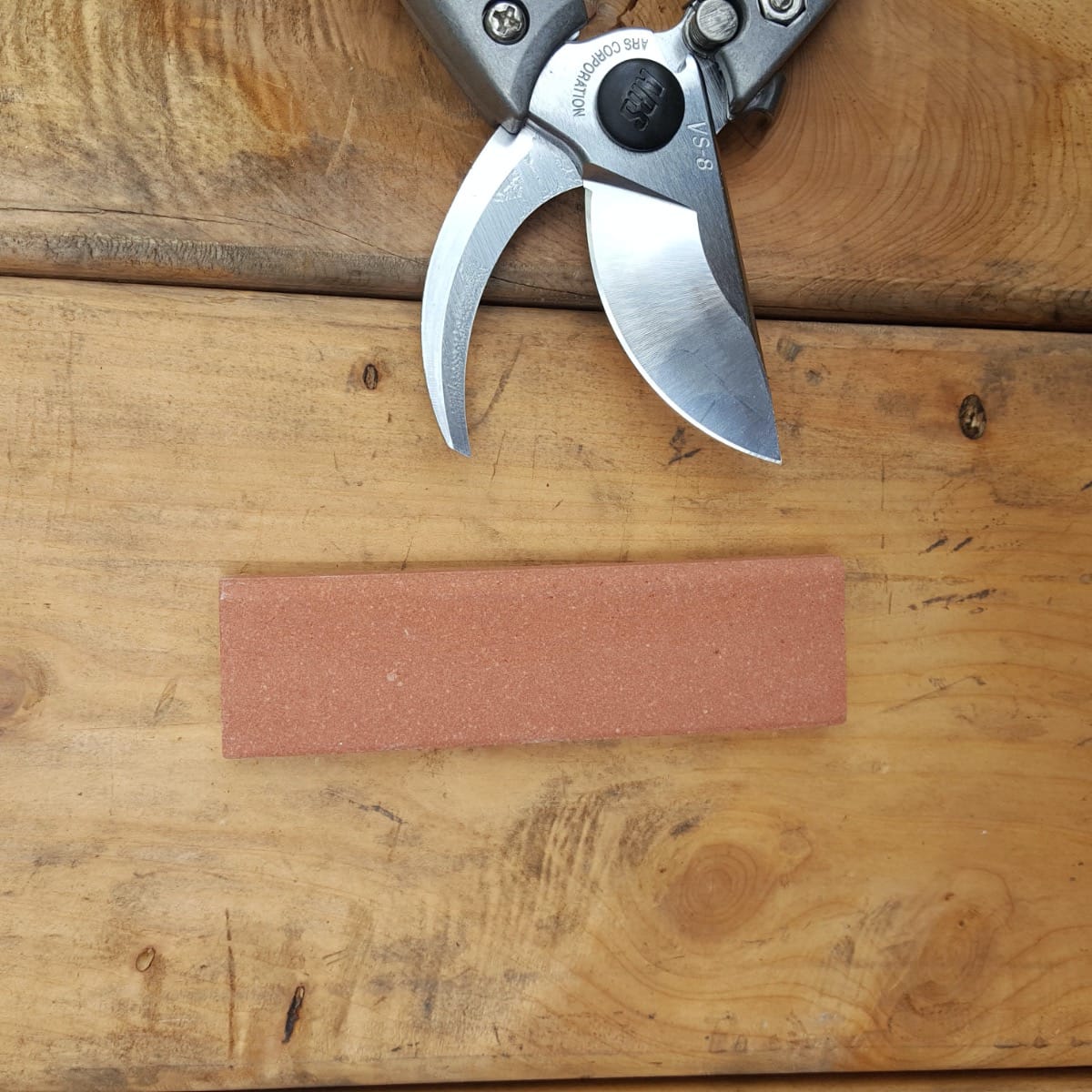 Medium grit whet stone shaped for sharpening pruners without disassembly.